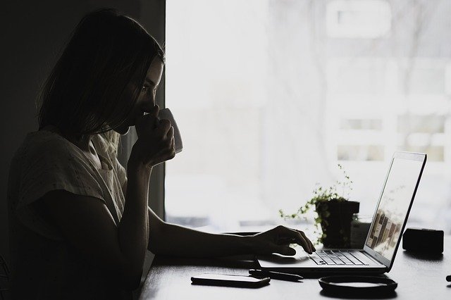 Girl drinking coffee and using laptop